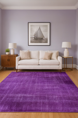 Living room with a purple rug, beige sofa, and sailboat artwork on the wall.