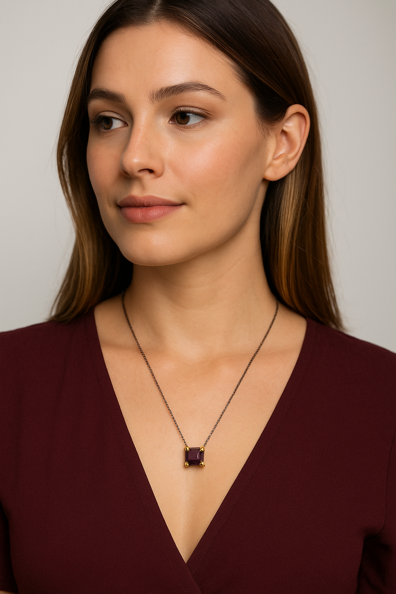 Woman wearing a deep V-neck top and a necklace with a pendant against a neutral background