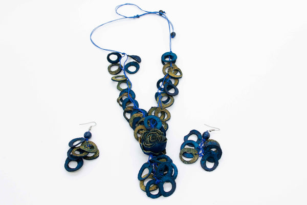 A blue beaded necklace with a variety of geometric shaped beads and a pair of matching earrings, all made from fruit peel and seeds.