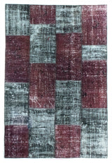 A patchwork rug made from vintage carpet pieces in shades of red and gray.